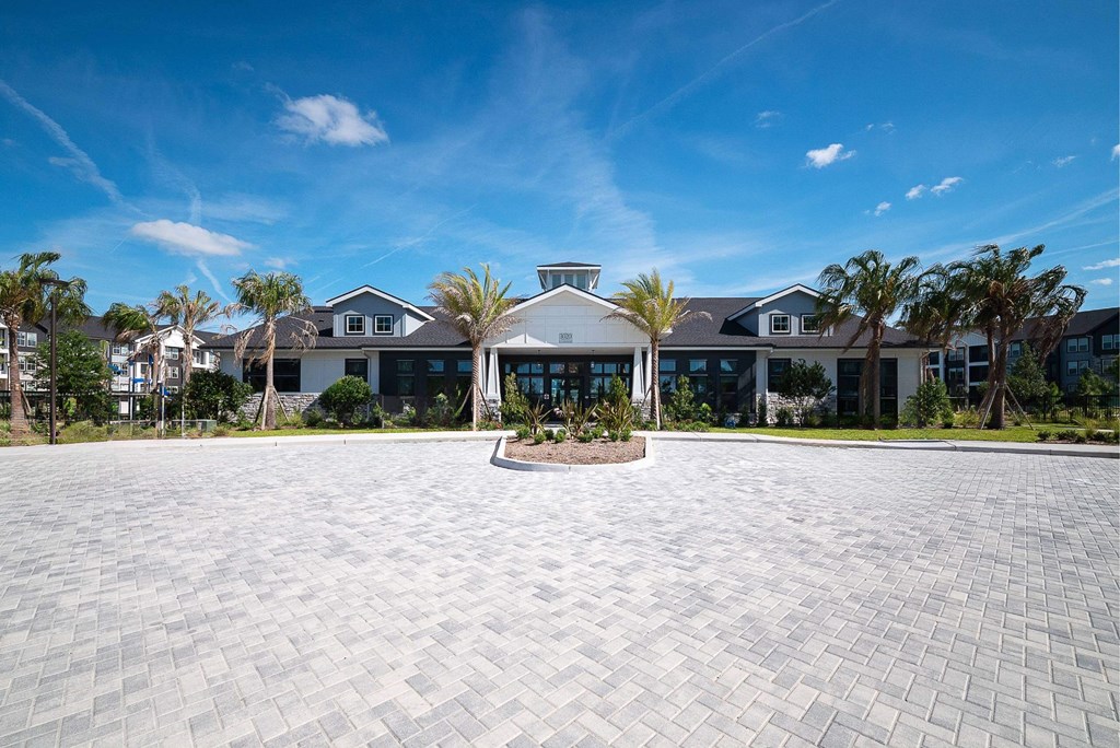 a mansion with a large driveway and a building with palm trees