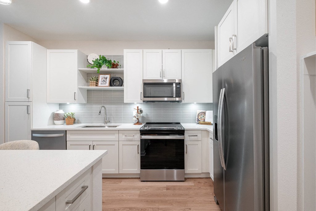 a white kitchen with stainless steel appliances and white cabinets