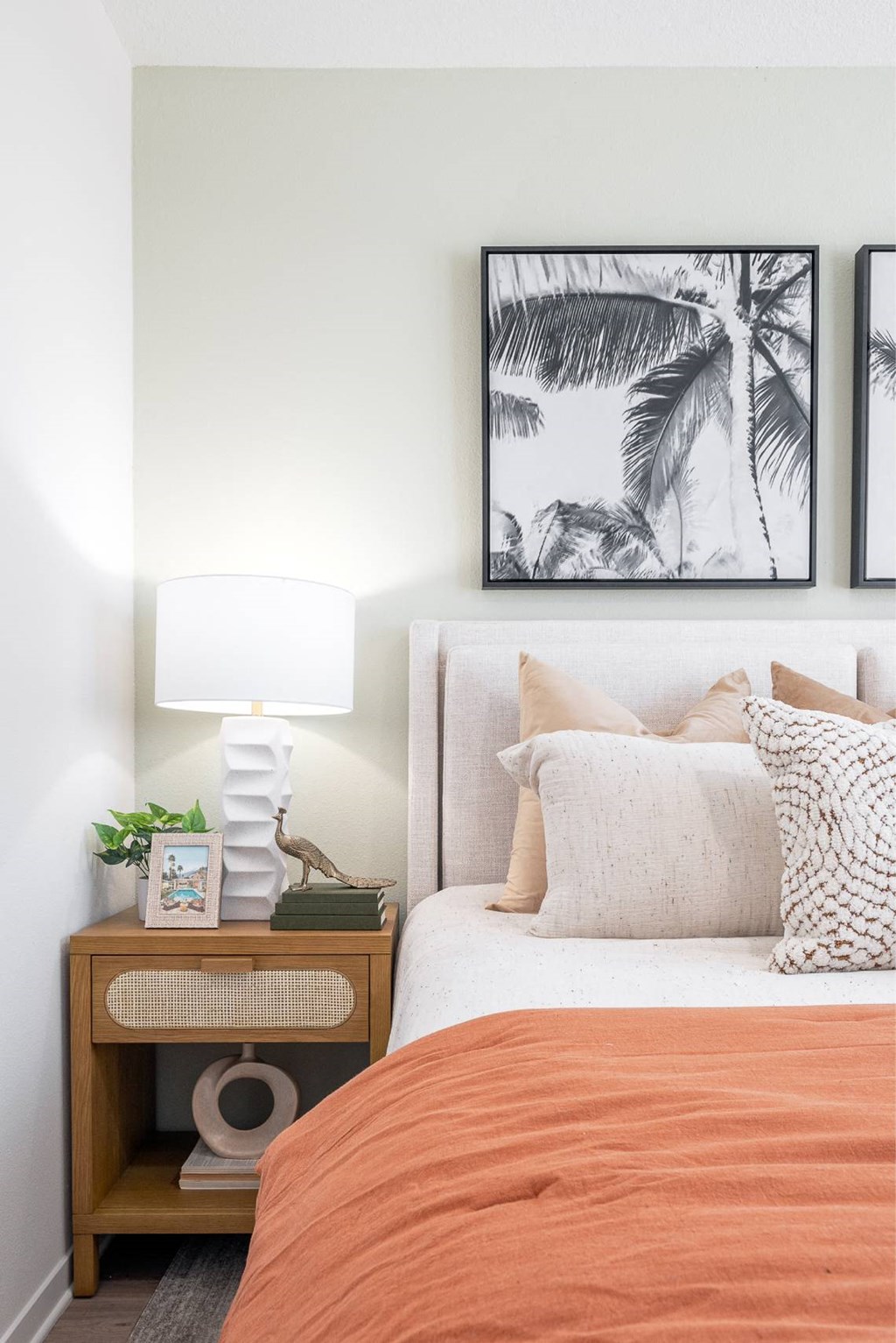 a bedroom with a bed and two pictures of palm trees on the wall