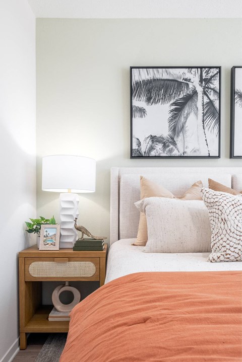 a bedroom with a bed and two pictures of palm trees on the wall