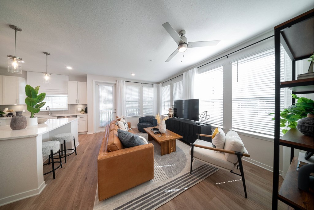 a living room with a couch and a kitchen with a ceiling fan