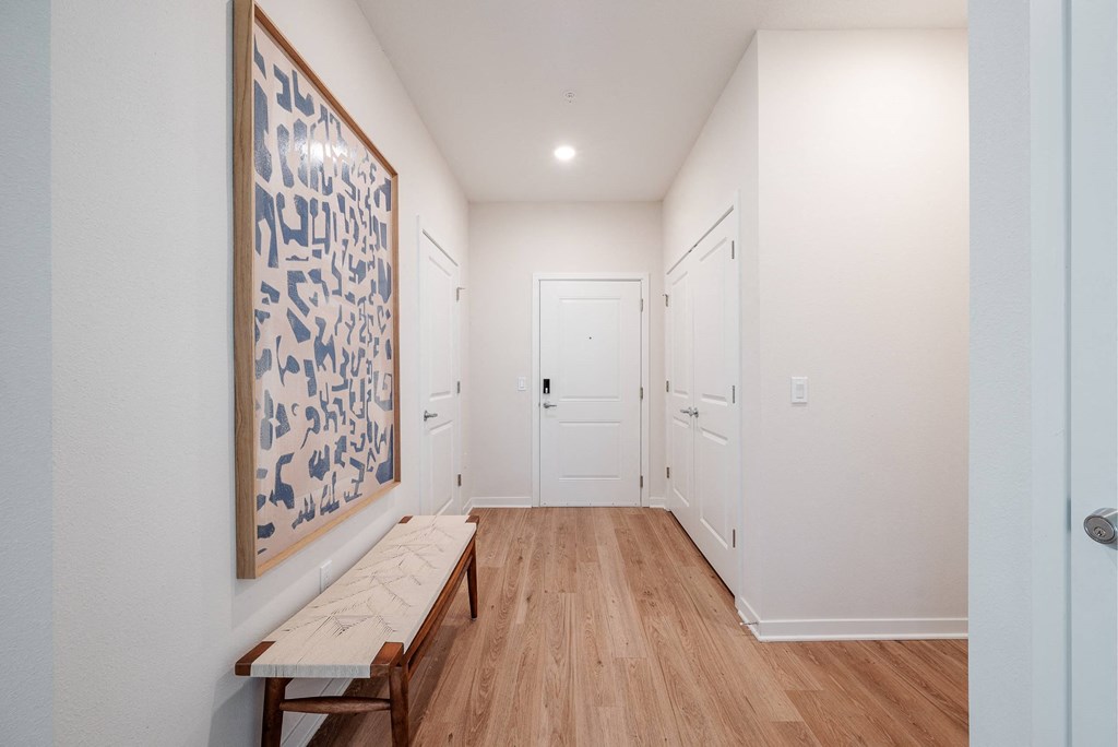 a hallway with a bench and a painting on the wall and white doors