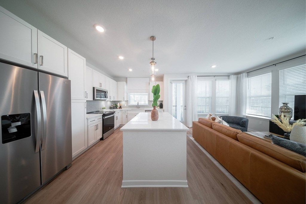 a kitchen and living room with white cabinets and stainless steel appliances