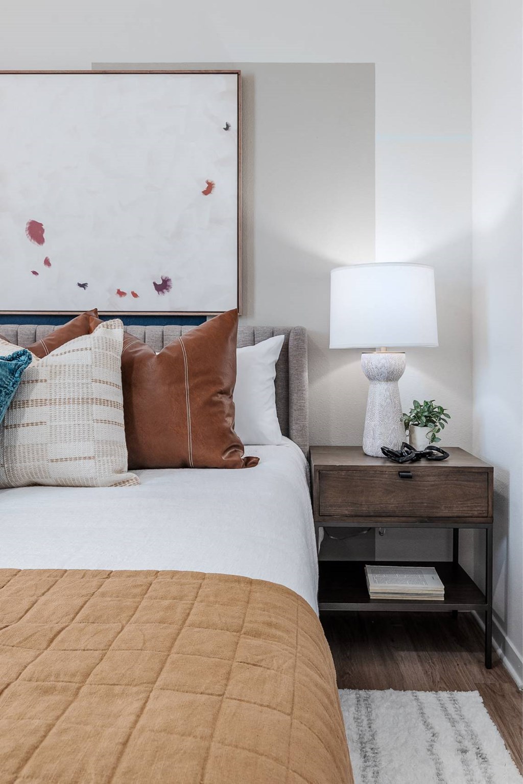 a bedroom with a bed and a lamp and a painting on the wall