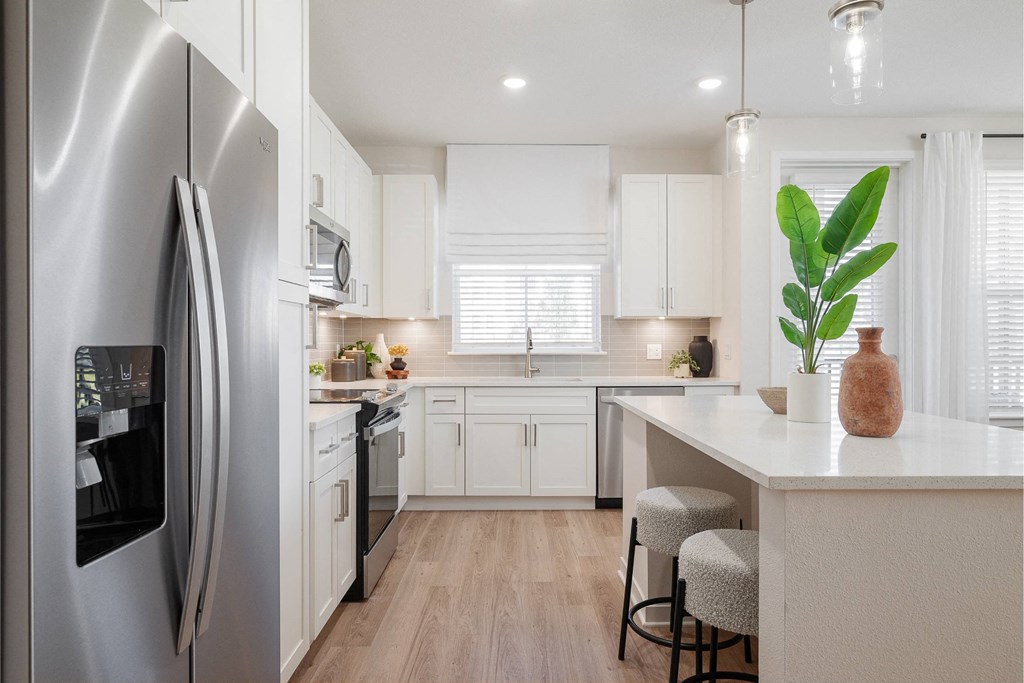a white kitchen with stainless steel appliances and a white counter top