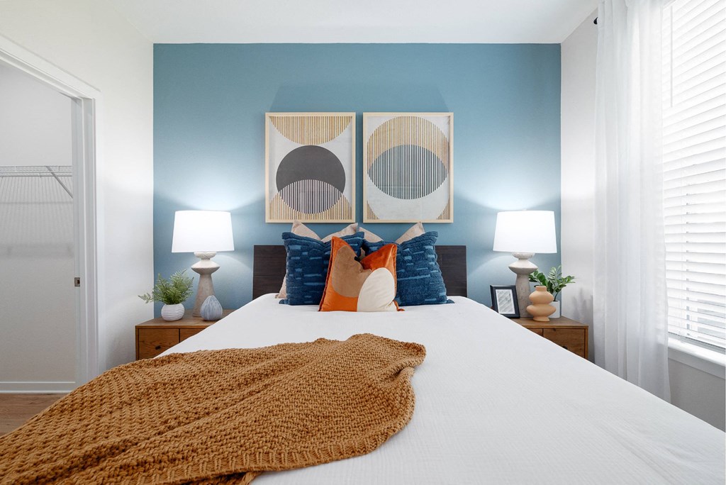 a bedroom with blue walls and a bed with orange and blue pillows