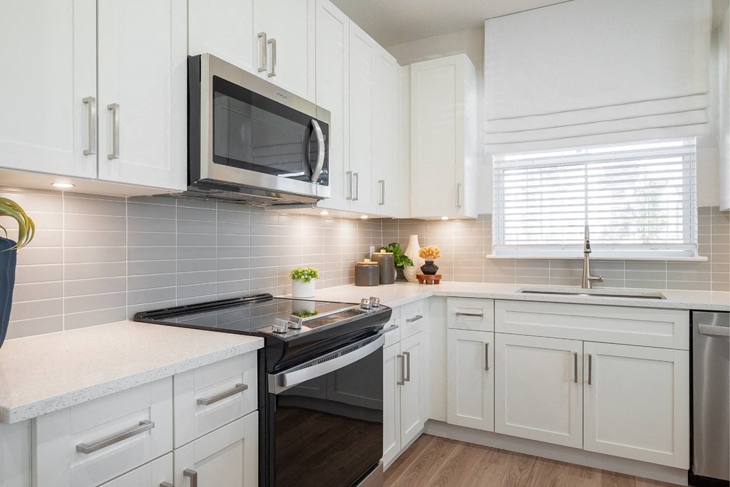 a kitchen with white cabinets and a stove and a microwave