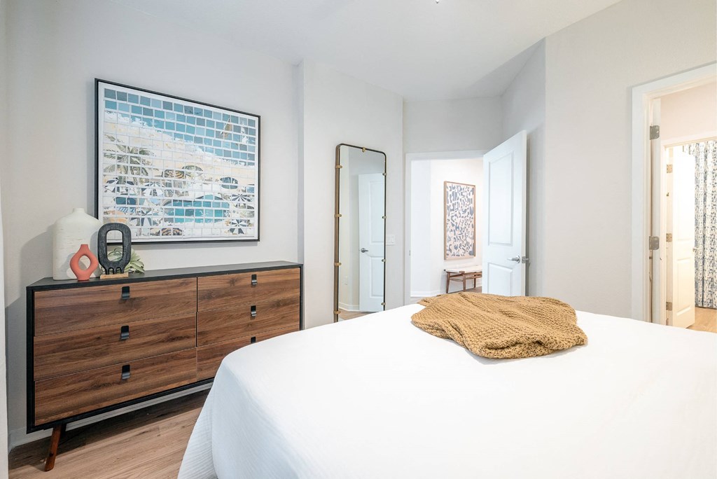 a bedroom with a large bed and a dresser with a mirror