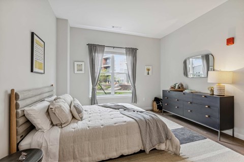 a bedroom with a bed and a dresser and a window