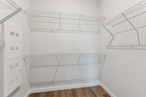 the walk in closet of a bedroom with white walls and metal shelves