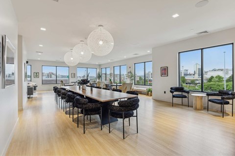 a dining room with a long table and chairs and large windows