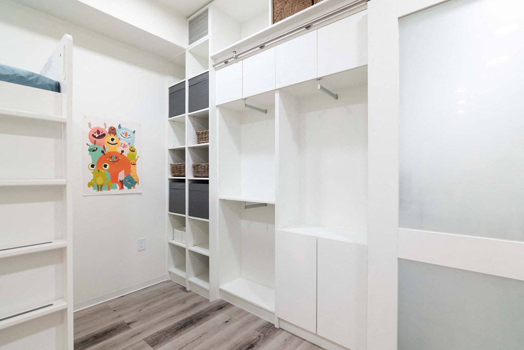 a walk in closet with white cabinets and a painting on the wall