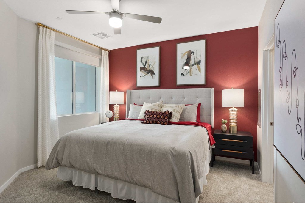 bedroom with red accent wall and bed with white bedspread and pillows