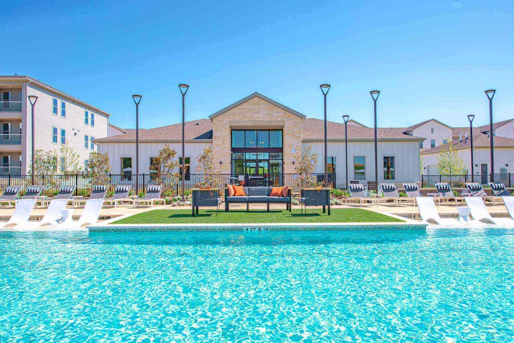 a swimming pool with lounge chairs in front of a building