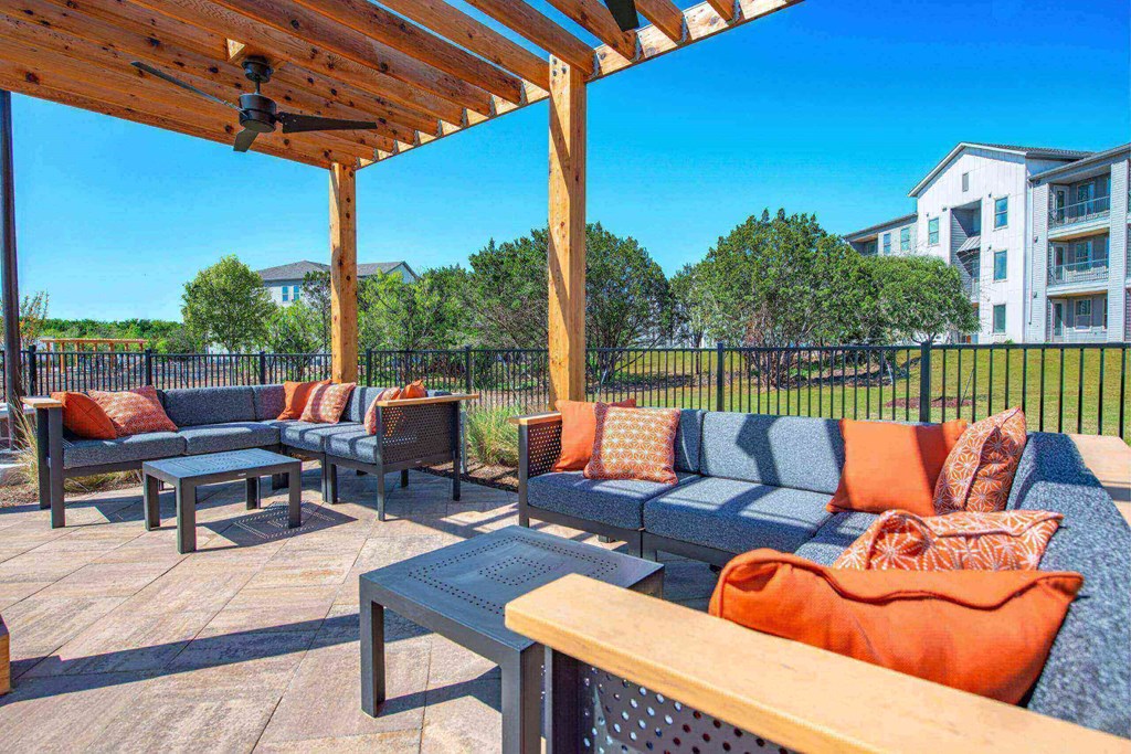 a patio with couches and tables and a pergola