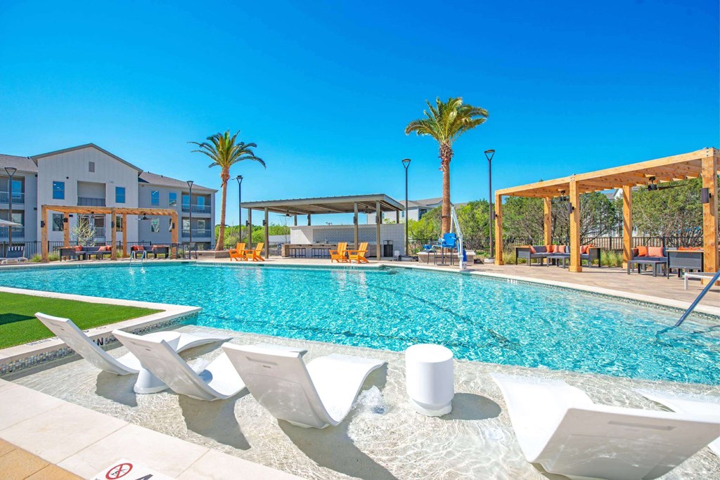 a swimming pool with chaise lounge chairs next to a resort style pool