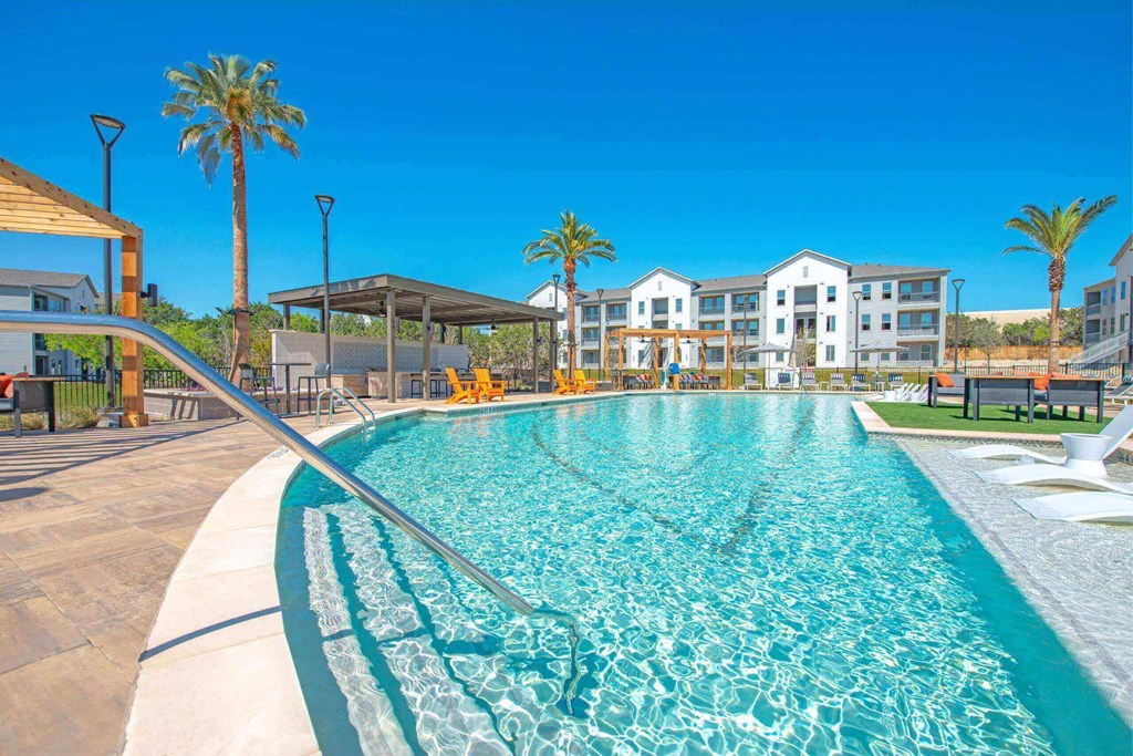 a swimming pool with palm trees and buildings in the background