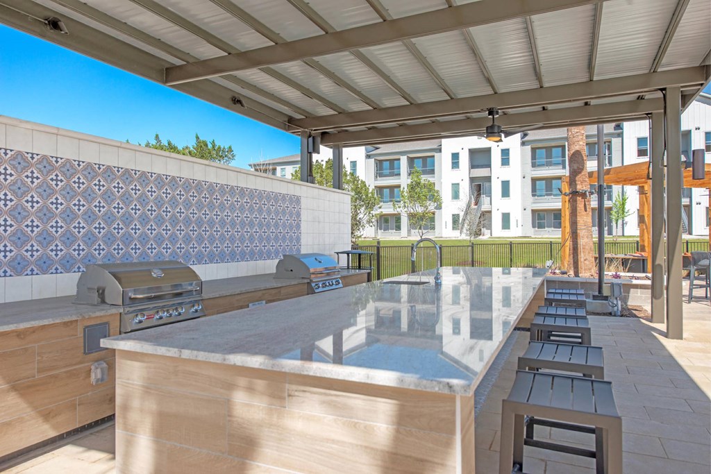 a patio with a grill and a bar with tables and chairs