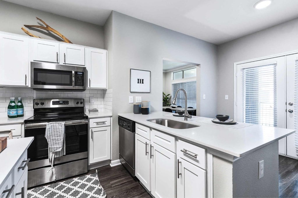 a white kitchen with stainless steel appliances and a sink