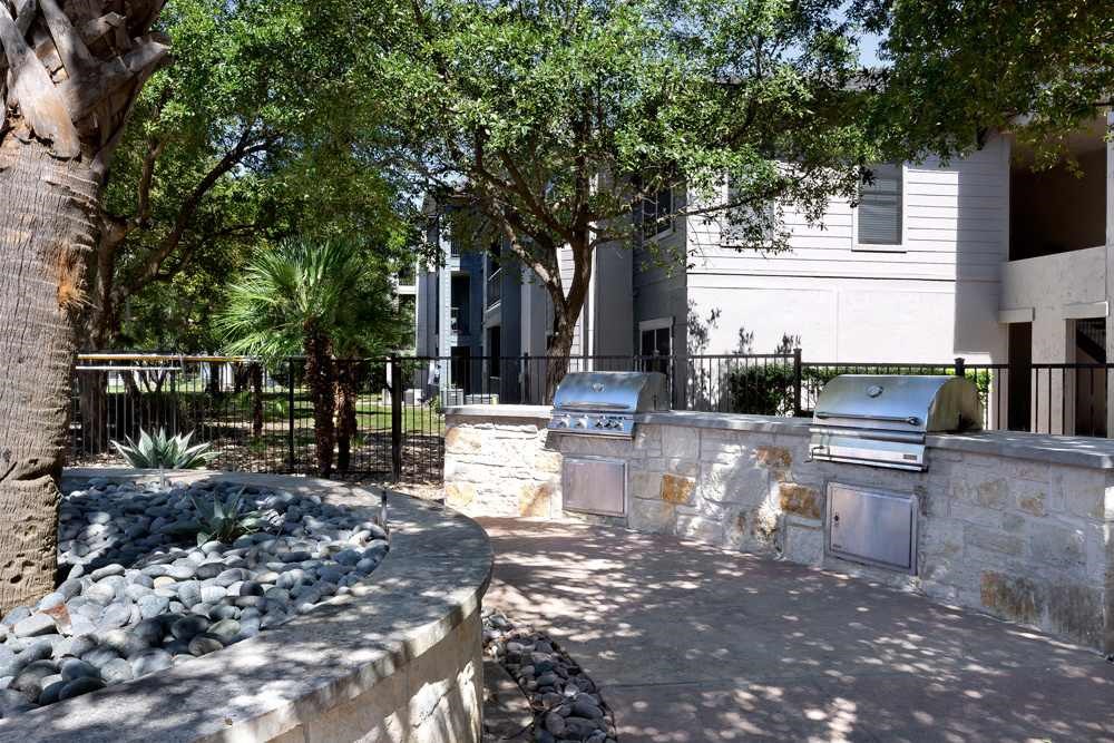 a stone wall with two barbecue grills in front of a building