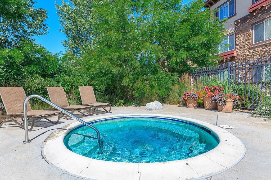 a hot tub in the backyard of a house with two chairs