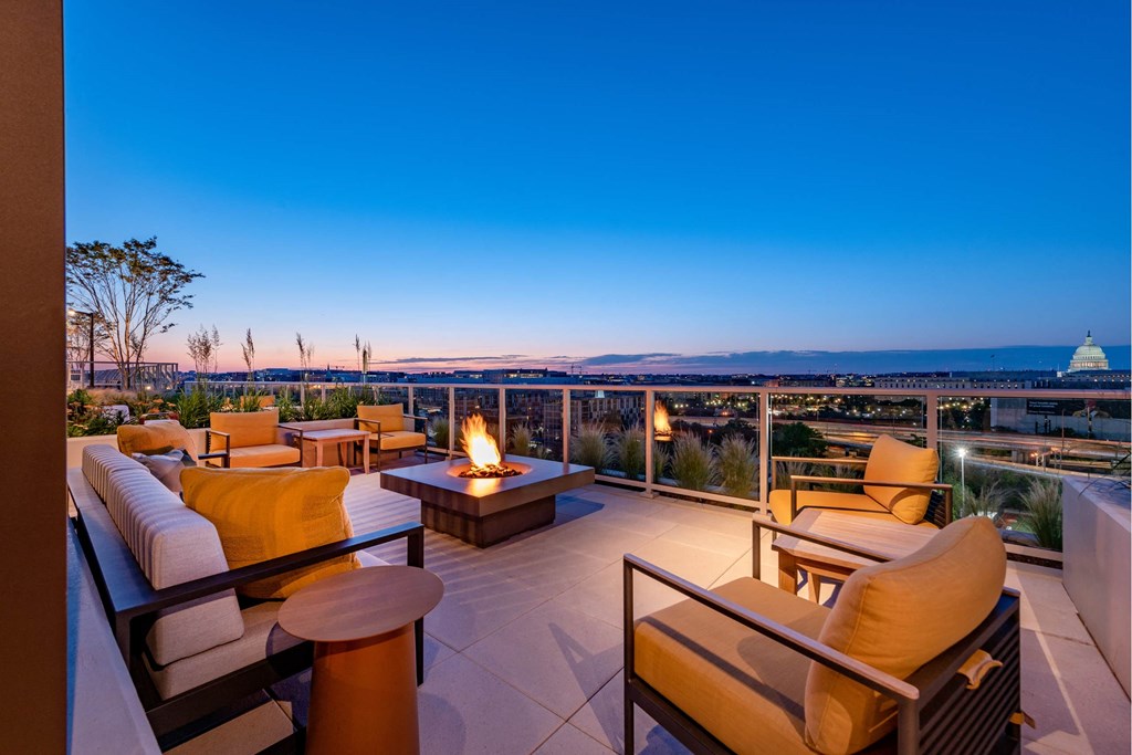 A patio with a fire pit and seating area overlooking a cityscape at dusk.