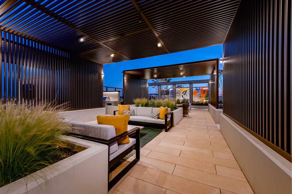 A modern outdoor seating area with a wooden ceiling and a stone floor.