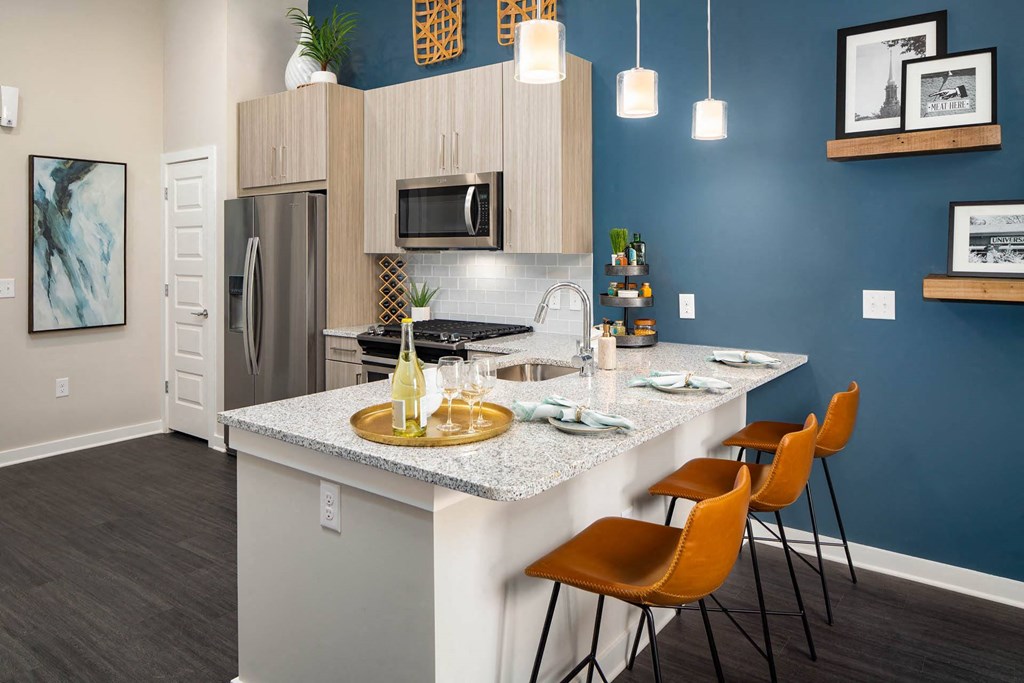 A kitchen with a white countertop and orange chairs.