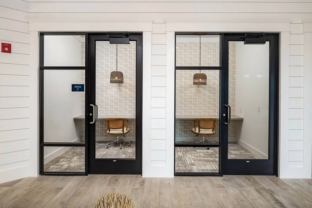 A room with two doors leading to a chair and a table in a study room.