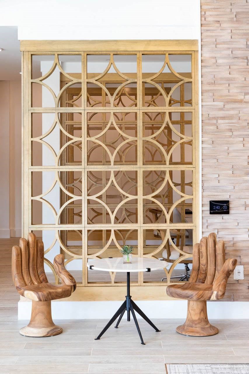 A wooden chair with a unique design is placed in front of a wooden lattice screen.