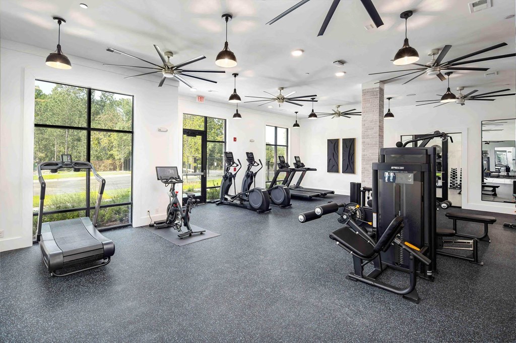 a gym with weights and cardio equipment and windows