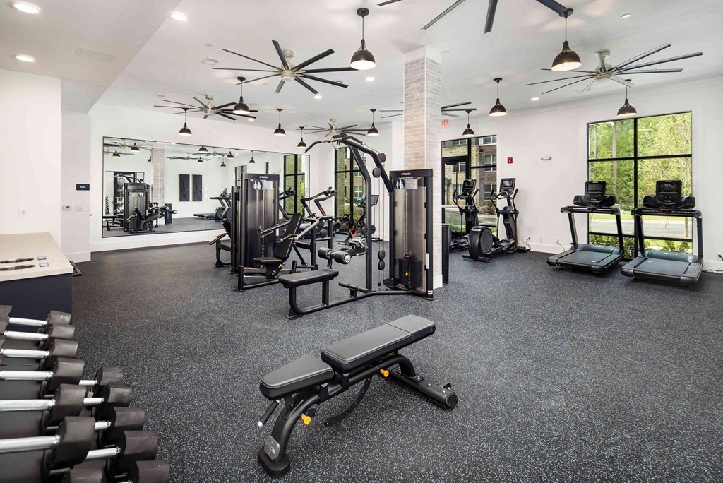 a gym with weights and cardio equipment in a building with windows