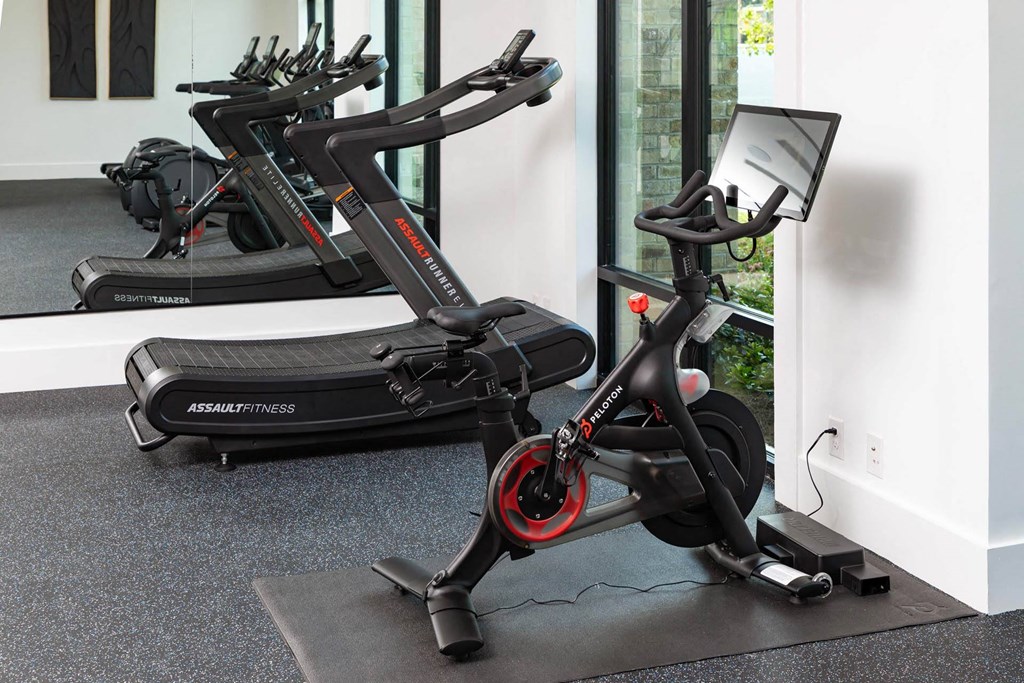 A black and red exercise bike is in a room with a grey floor.