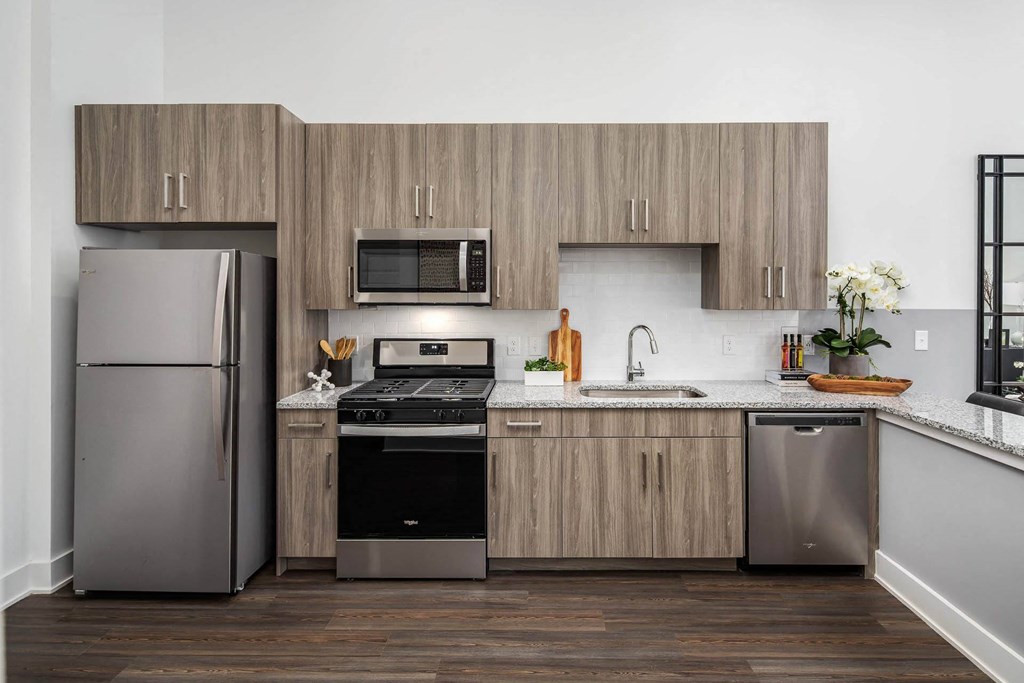 A modern kitchen with a refrigerator, oven, and sink.