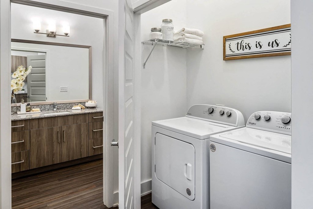 a white washer and dryer in a room with a mirror and a bathroom