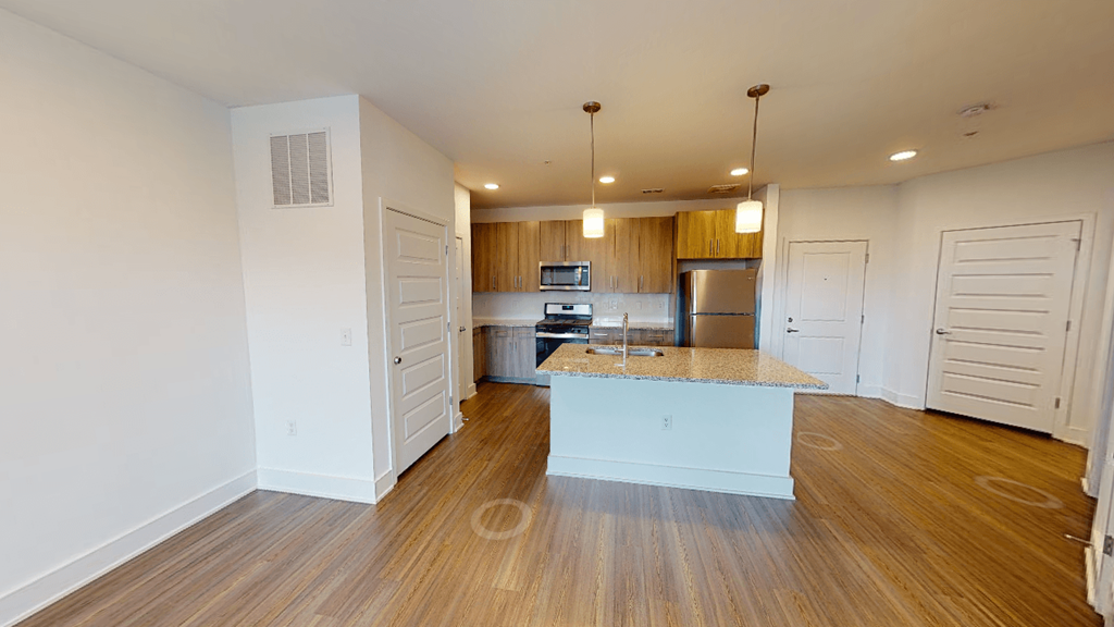 an empty living room with a kitchen with a counter top