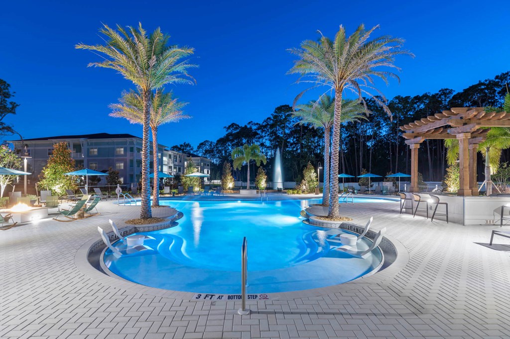 a swimming pool at night with palm trees