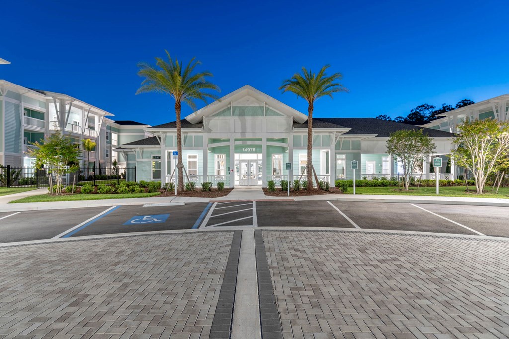 a large white house with palm trees in a parking lot