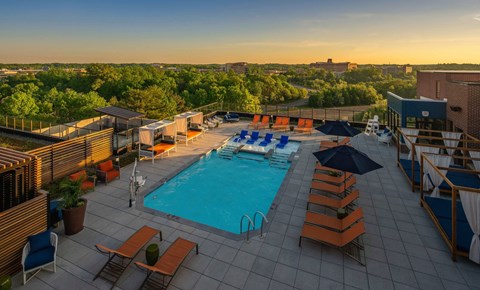 a swimming pool on the rooftop of a hotel with a city in the background