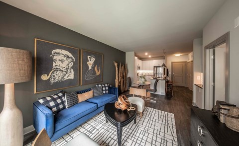 A living room with a blue couch and a black and white rug.