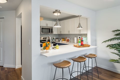 a kitchen with a white counter top and three stools