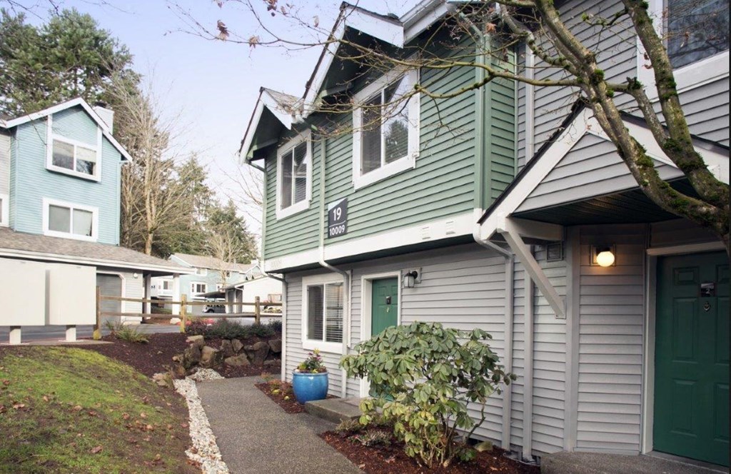 a green and white house with a sidewalk in front of it at Hidden River Townhomes, Kirkland, Washington