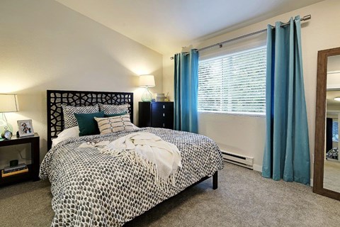 Bedroom with decorative headboard and patterned bedding at Hidden River Townhomes Apartments, Kirkland, 98034