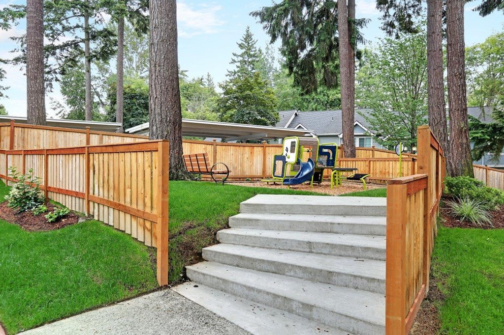 a wooden fence with stairs and a playground in a yard at Hidden River Townhomes, Kirkland, Washington