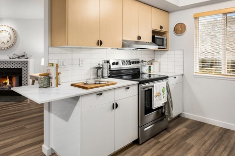 a kitchen with white cabinets and a stove and a fireplace at Scout, Kirkland, WA