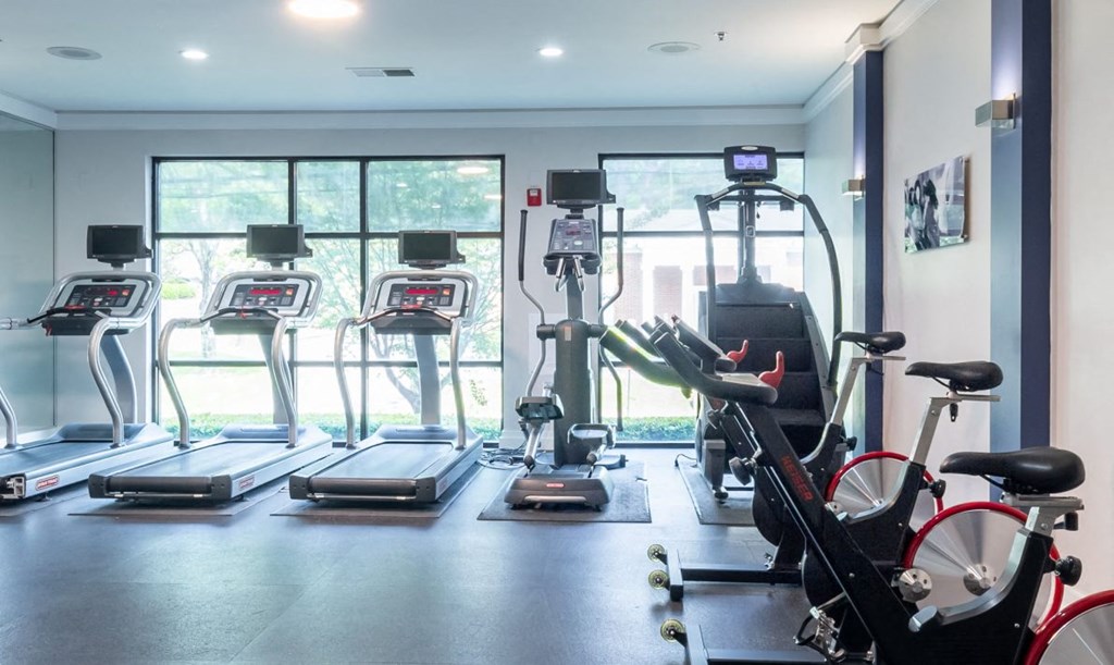 a gym with cardio equipment and a large window