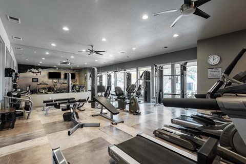 a gym with weights and cardio machines and a clock