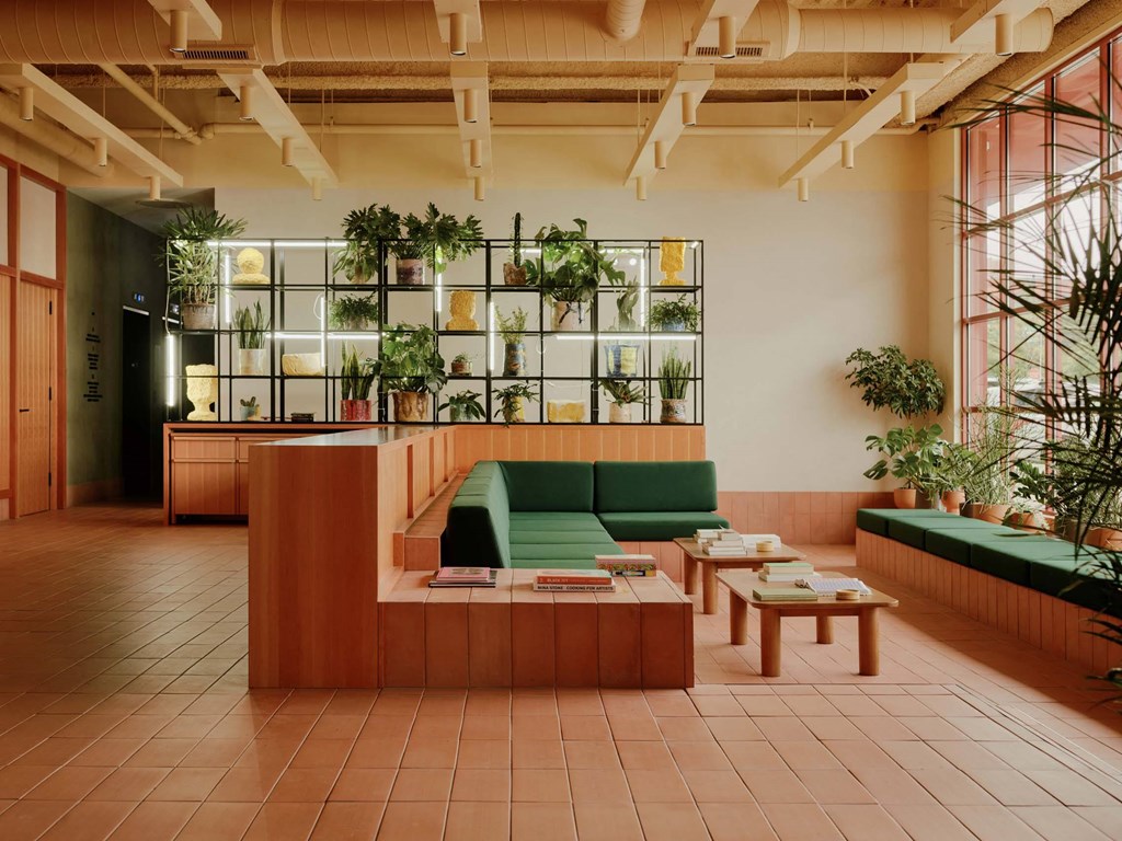 a lobby with green couches and tables and a kitchen