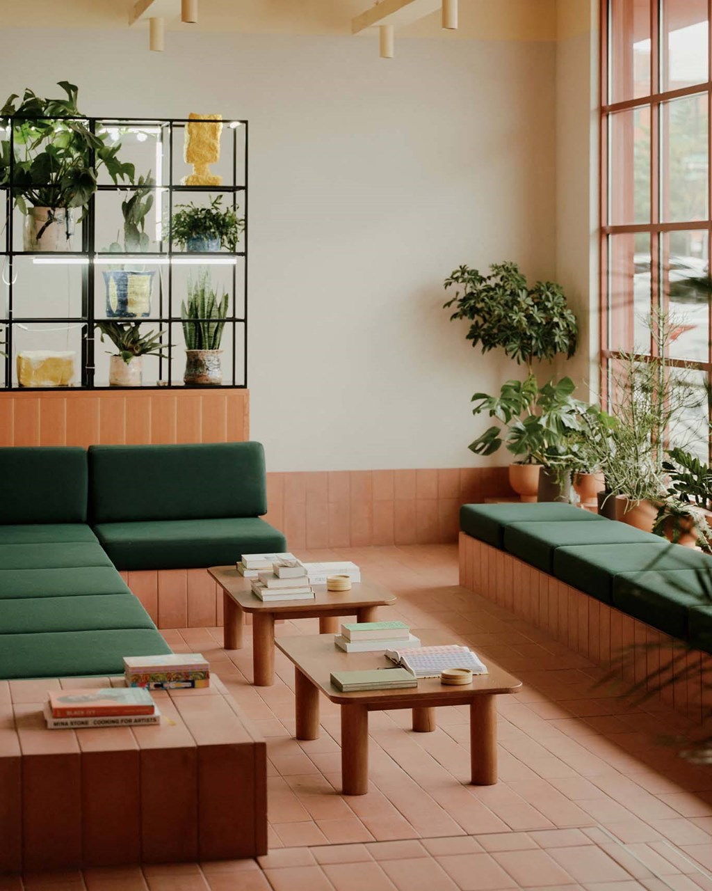 a room with green couches and tables and plants