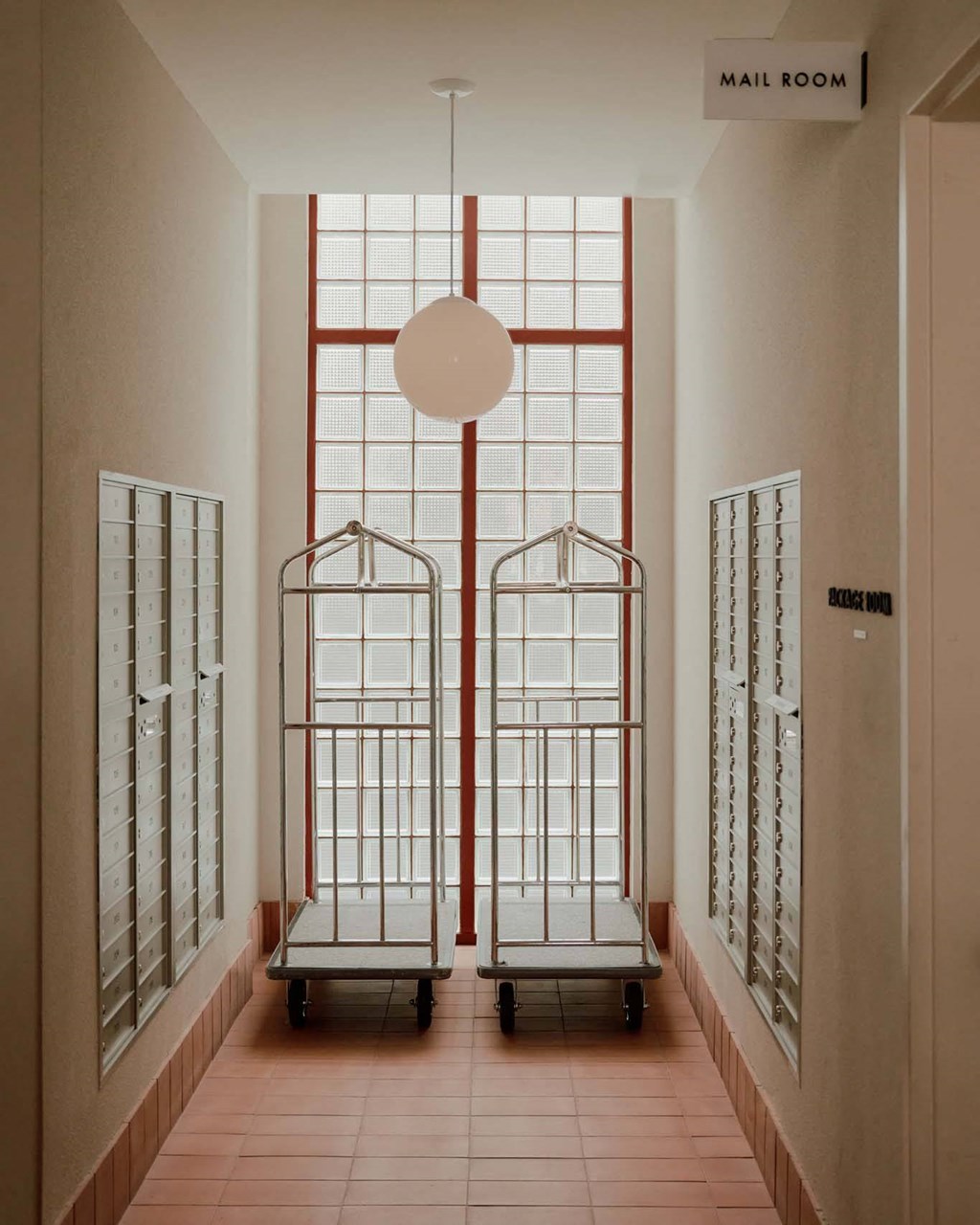 a long hallway with prison cells and a light hanging from the ceiling